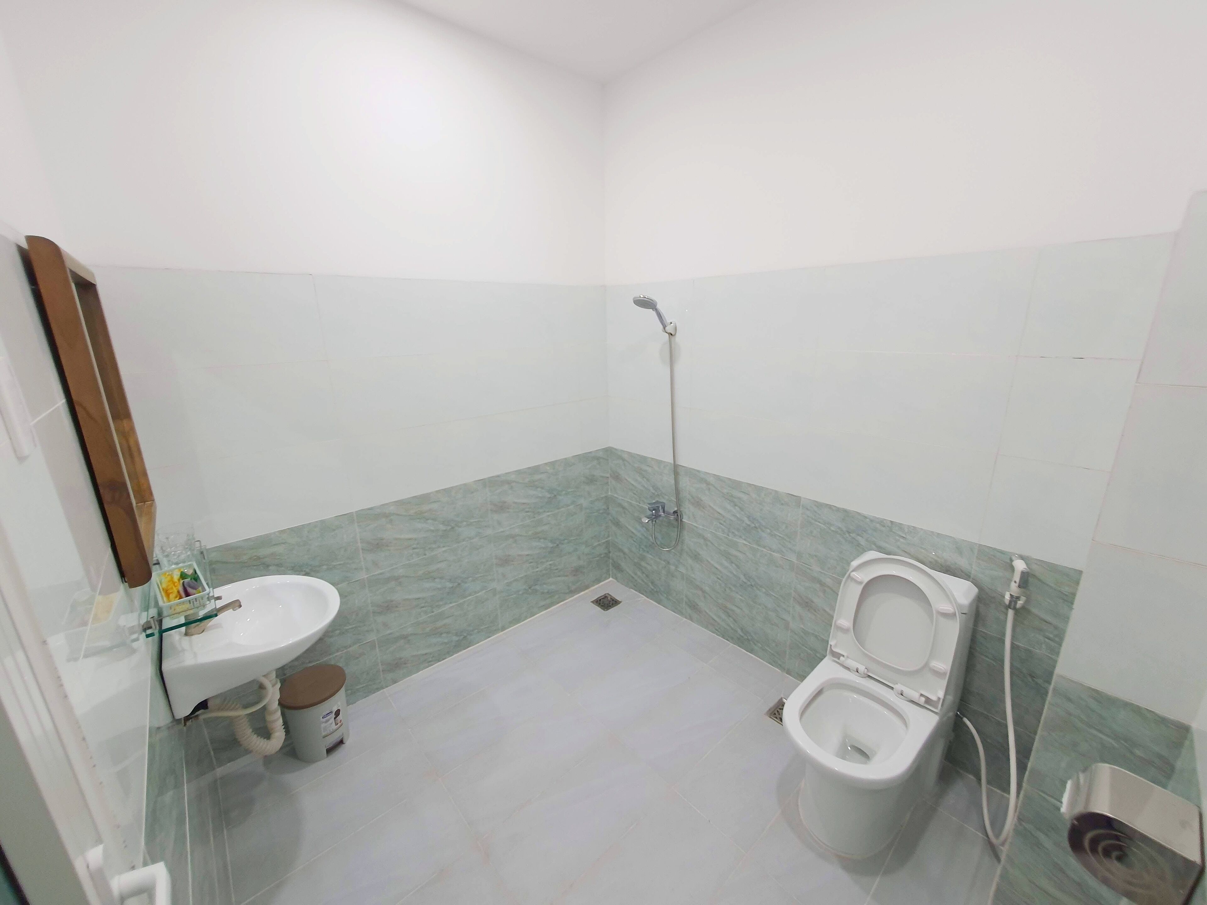 A small bathroom with a toilet, sink, and shower.