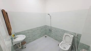 A small bathroom with a toilet, sink, and shower.