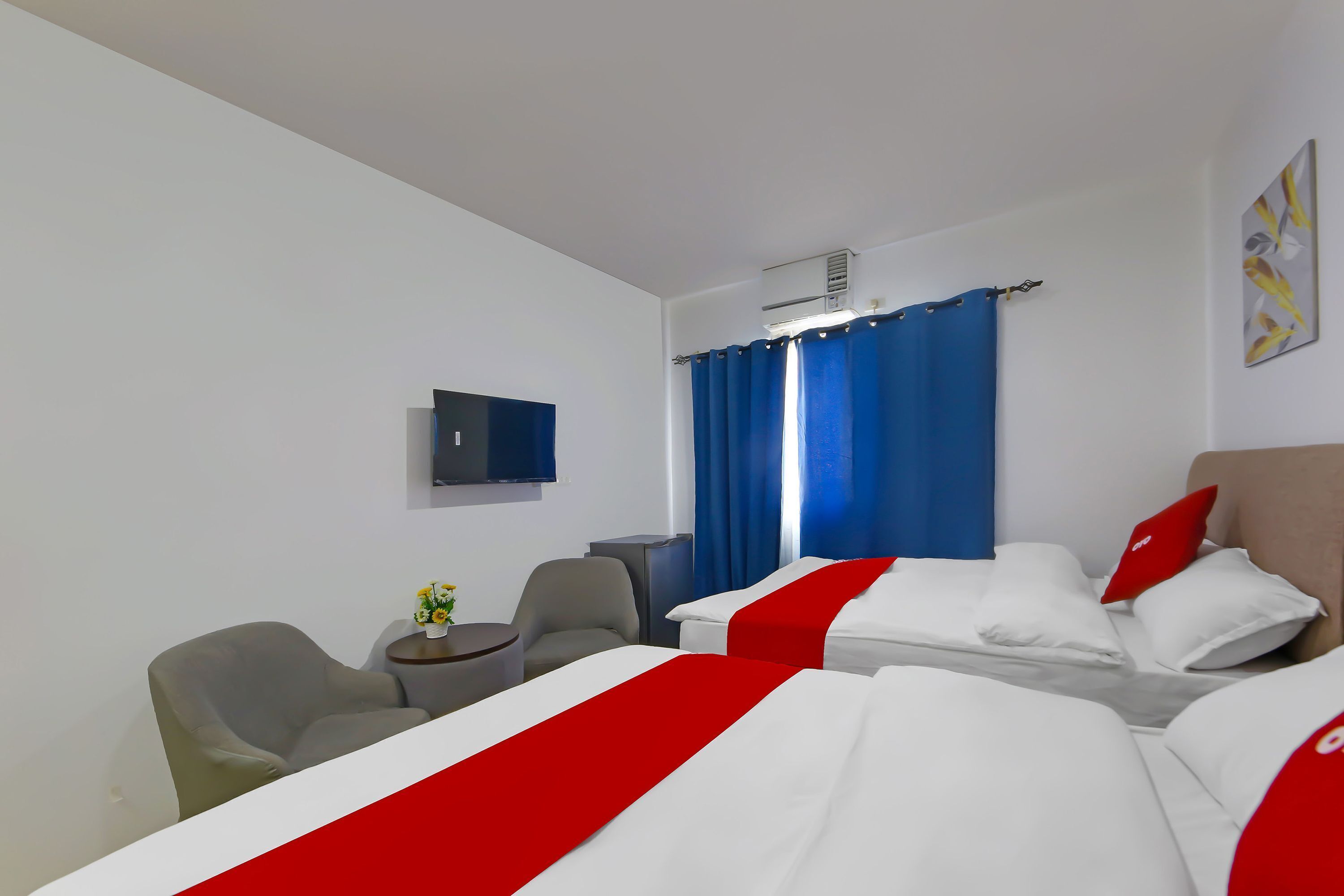 Une chambre d’hôtel avec deux lits, une télévision, un bureau et une chaise.