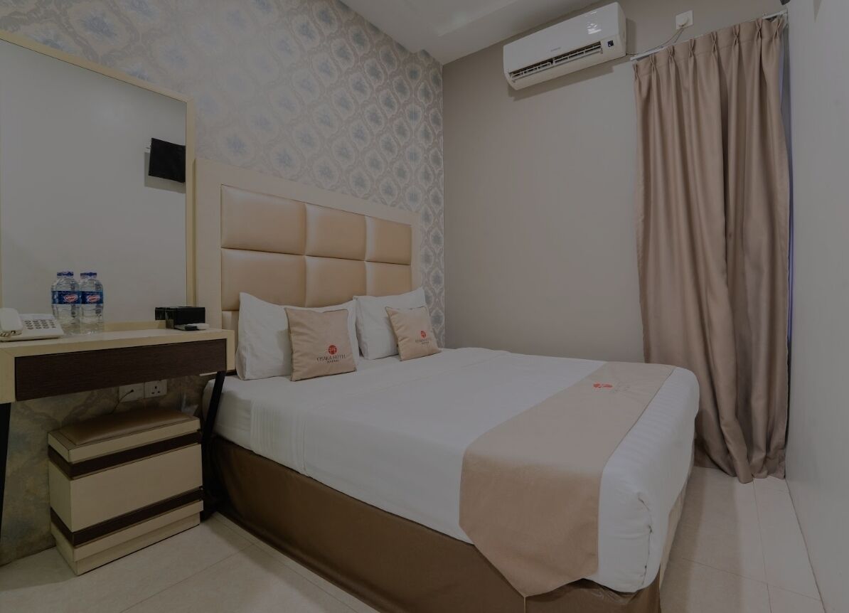 A hotel room with a bed, bedside table, and a mirror.