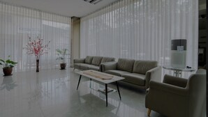 A modern living room with a sofa, a coffee table, and two potted plants. - osaka hotel batam (Batam)