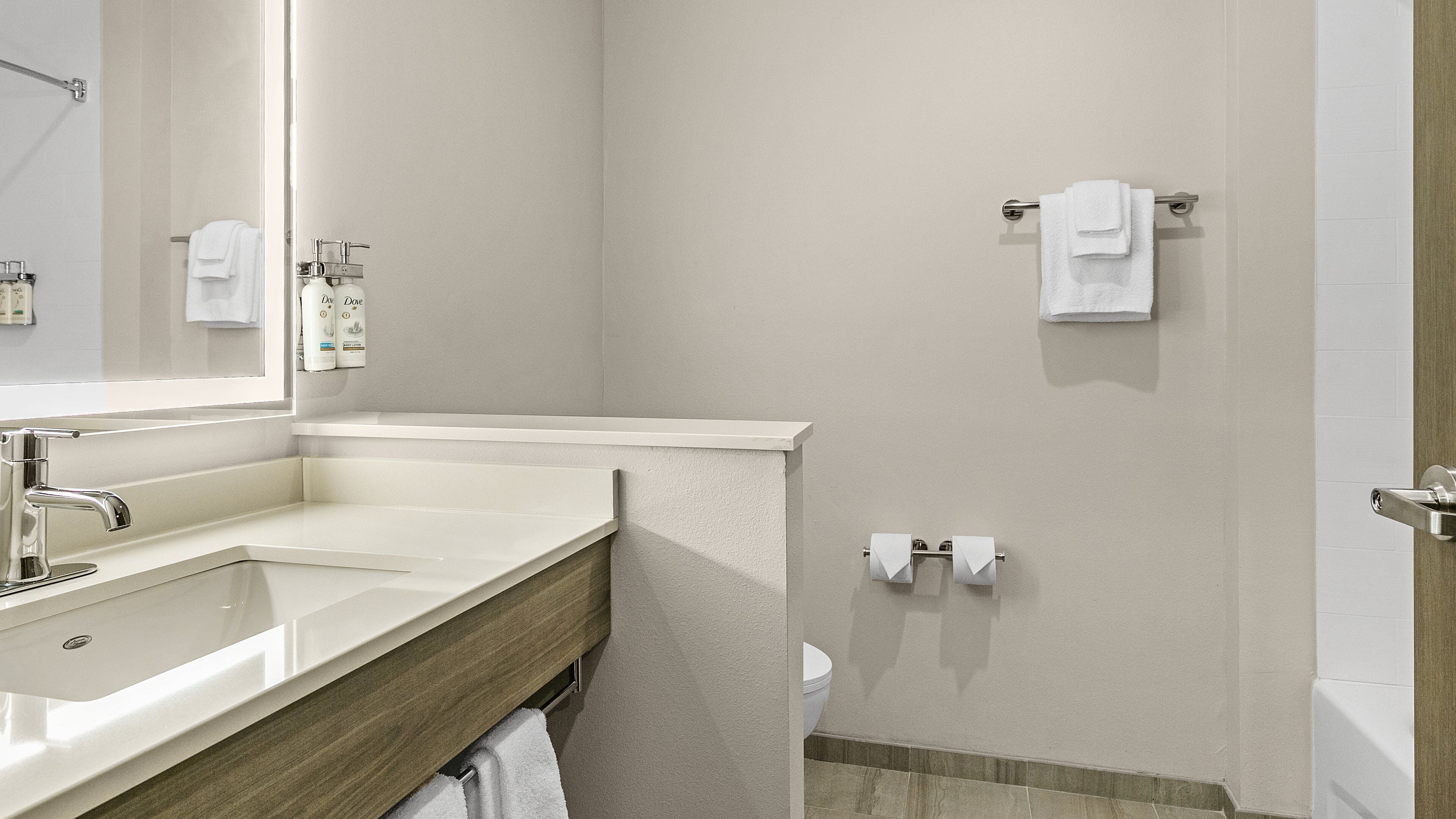 Un baño con lavamanos, espejo, toallero, inodoro y zona de ducha.