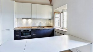 Eine moderne Küche mit weißen Schränken, einer großzügigen Kücheninsel und einem Fenster, das für natürliches Licht sorgt.