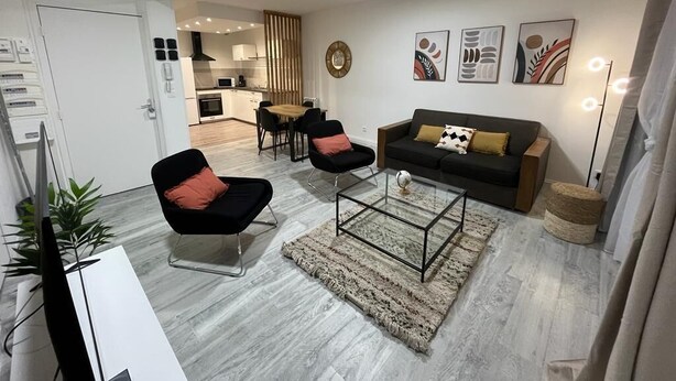 A modern living room with a sofa, two armchairs, a coffee table, and a dining area in the background. - LeRelaisdOdile * Spacious & Bright Apartment * (Cambrai)