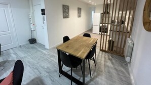 A modern dining area with a wooden table and black chairs, a white door, and a radiator on the wall. - LeRelaisdOdile * Spacious & Bright Apartment * (Cambrai)