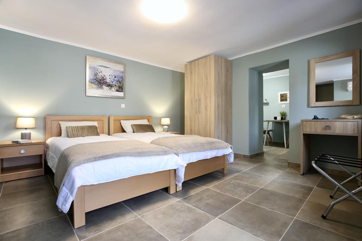 A bedroom with a double bed, bedside tables, a desk, and a mirror.