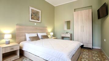 A bedroom with a bed, nightstands, a dresser, a mirror, and a television.