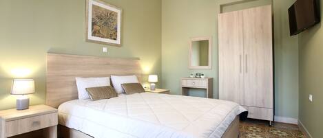 A bedroom with a bed, nightstands, a dresser, a mirror, and a television.