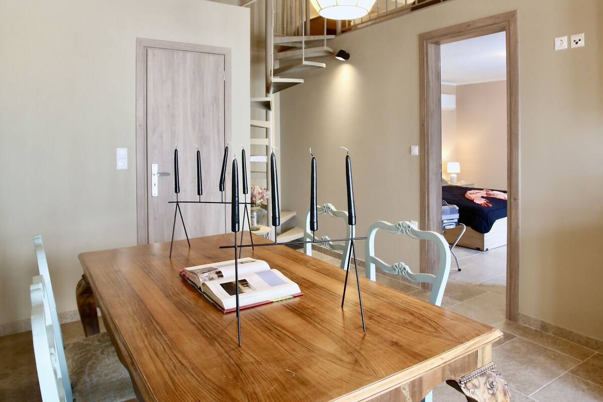A dining area with a wooden table, chairs, and a staircase leading to an upper level.