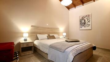 Un dormitorio con cama, lámparas de noche, una silla roja y una obra de arte en la pared.