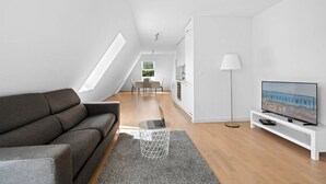 Una sala de estar moderna con un sofá, una televisión y un comedor con una mesa y sillas.