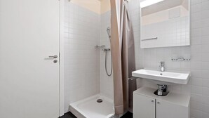 Un baño moderno con ducha, lavamanos e inodoro.