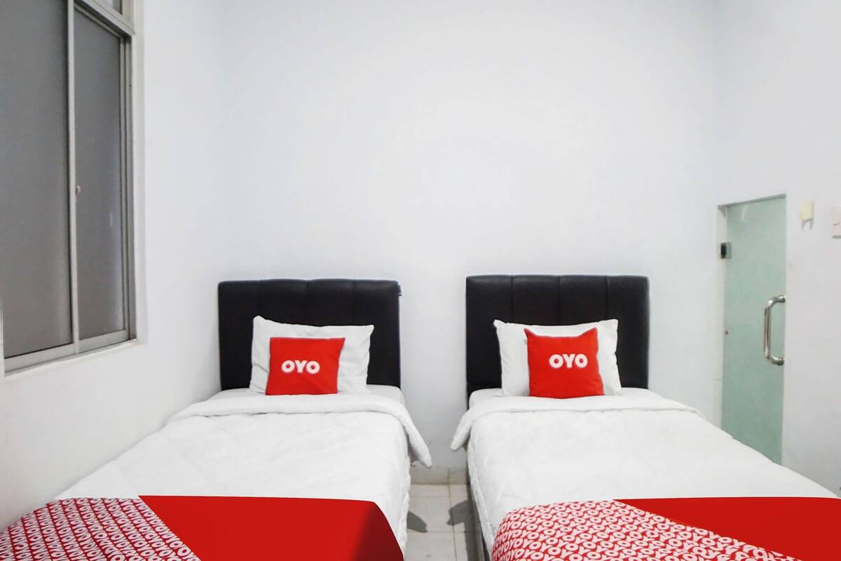 A room with two beds, each with a black headboard and a red pillow with the word "OYO".