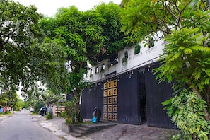 A street lined with trees and a building with a black gate and a large decorative door.