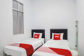 A room with two beds, each with a white and red bedspread and a pillow with "OYO" branding.