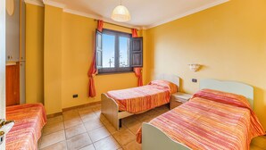 A room with two single beds, a window with curtains, a hanging light fixture, and a radiator. - Beautiful Apt With Seaview Terrace (Pisciotta)