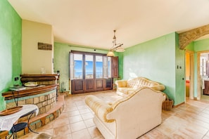 A living room with a sofa, a small table, a stone fireplace, and a view through a door.