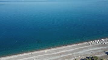 Di pantai, kursi berjemur, payung pantai, dan handuk pantai