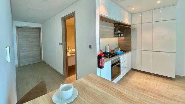 Cozinha moderna com armários brancos, forno embutido e um espaço para café.