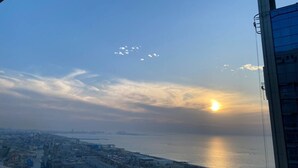 Vista urbana com o mar e um pôr do sol.