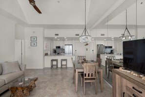 A modern living room with a sofa, coffee table, and dining area with chairs and a TV.