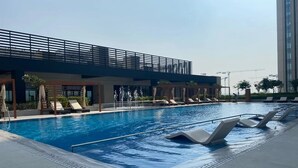 Una piscina con sillas de descanso y una zona techada.