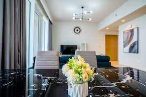 A modern living room with a marble coffee table, a floral centerpiece, and a contemporary chandelier.