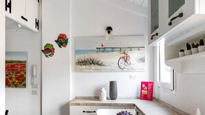 Une cuisine moderne avec des meubles blancs, un plan de travail en granit et un coin repas agrémenté d’une chaise blanche.