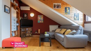 Un loft acogedor con techo inclinado, un sofá gris, una mesita y una estantería.