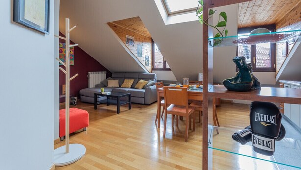 Un loft moderno con comedor, sala de estar con sofá y cocina con mesa de vidrio.
