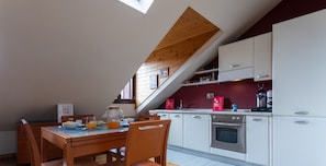 A modern kitchen with white cabinets, a wooden dining table, and a breakfast setup.