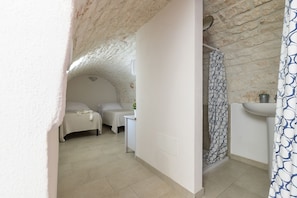 Cozy retreat with a single bed, nightstand, and shower area, perfect for a simple stay.