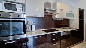 Une cuisine moderne dotée d’appareils électroménagers en acier inoxydable, de meubles de rangement aux couleurs sombres et d’un plan de travail élégant.