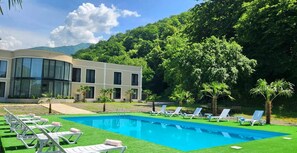 Un hôtel moderne doté d’une piscine, de chaises longues et d’un paysage verdoyant luxuriant.