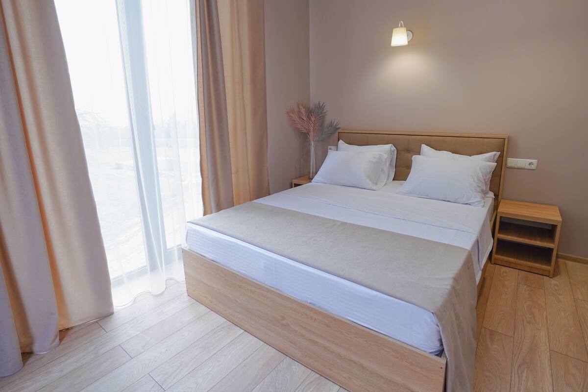 A neatly made bed with white linens, a wooden headboard, and a bedside table with a lamp.