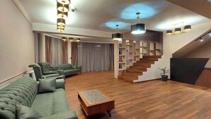 Ein modernes Wohnzimmer mit einer Sofagarnitur, Holzböden und einer Treppe, die zu einer oberen Ebene führt.