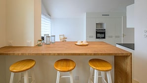 Een moderne keuken met een houten kookeiland, drie barkrukken en een inbouwoven.