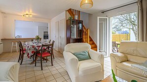 Een goed verlichte kamer met een eettafel voor vier personen, een bank en een trap naar een hoger niveau.