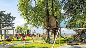 Een speeltuin met schommels, glijbanen en een boomhuis.