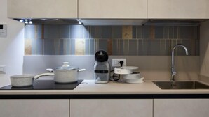 Une cuisine moderne avec un plan de travail noir, une machine à café, une bouilloire et un évier.