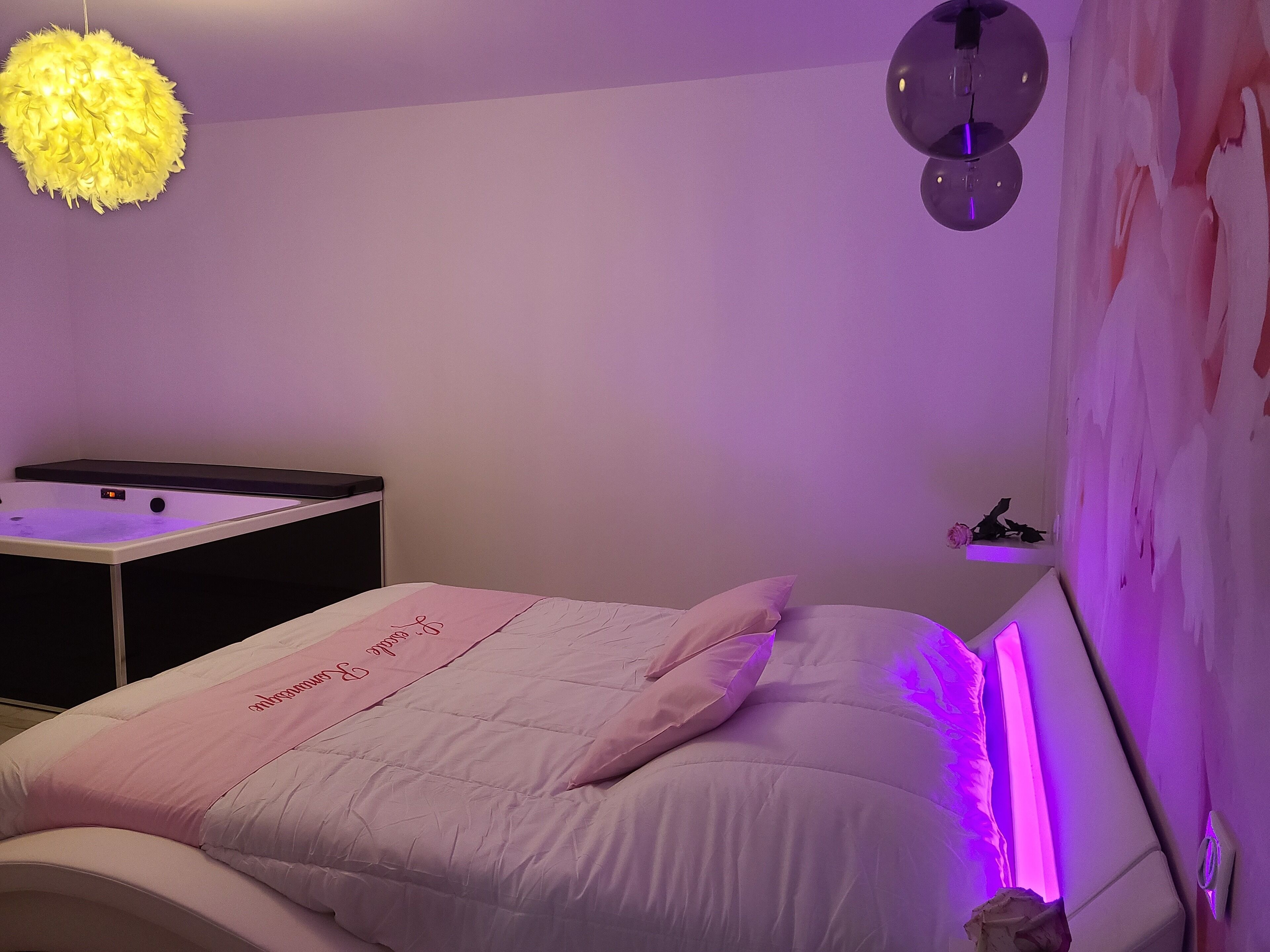 Un dormitorio con cama, una mesita de noche, un espejo en la pared y un adorno mural.