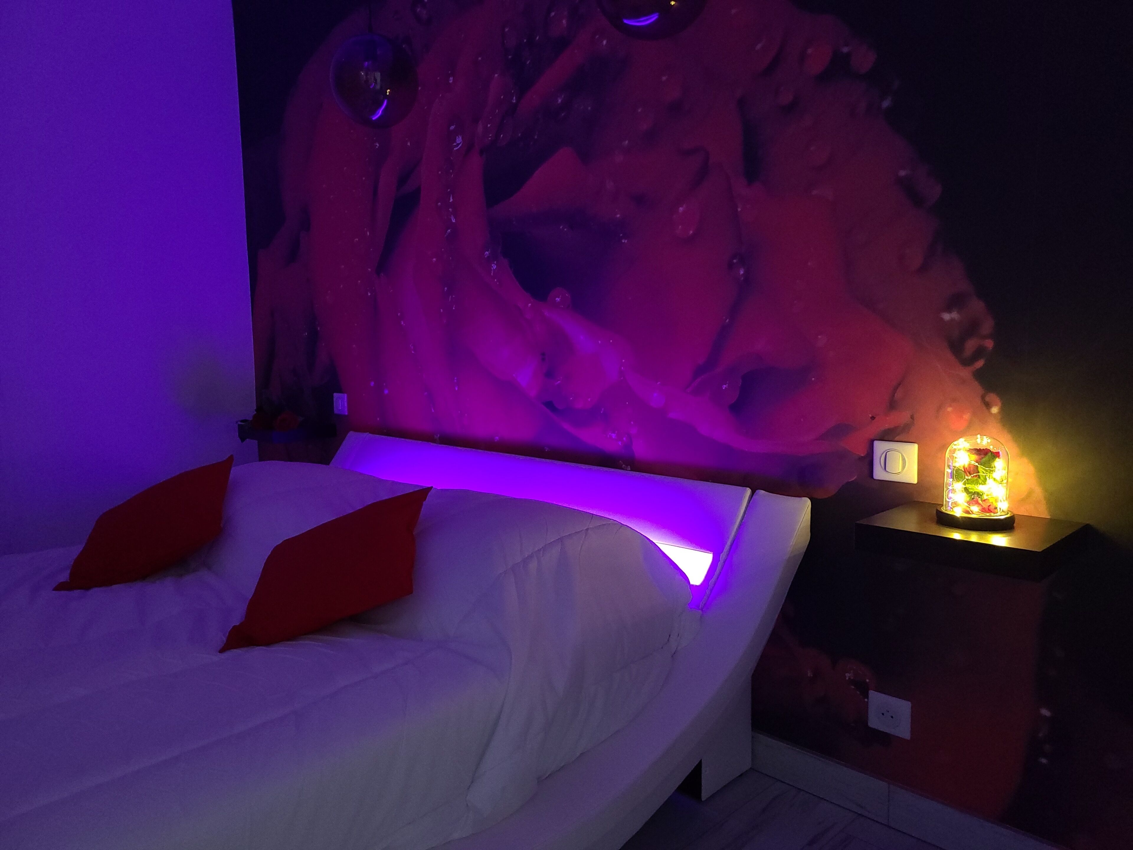 Une chambre à coucher avec un lit, une table de chevet avec une lampe et une fresque murale.