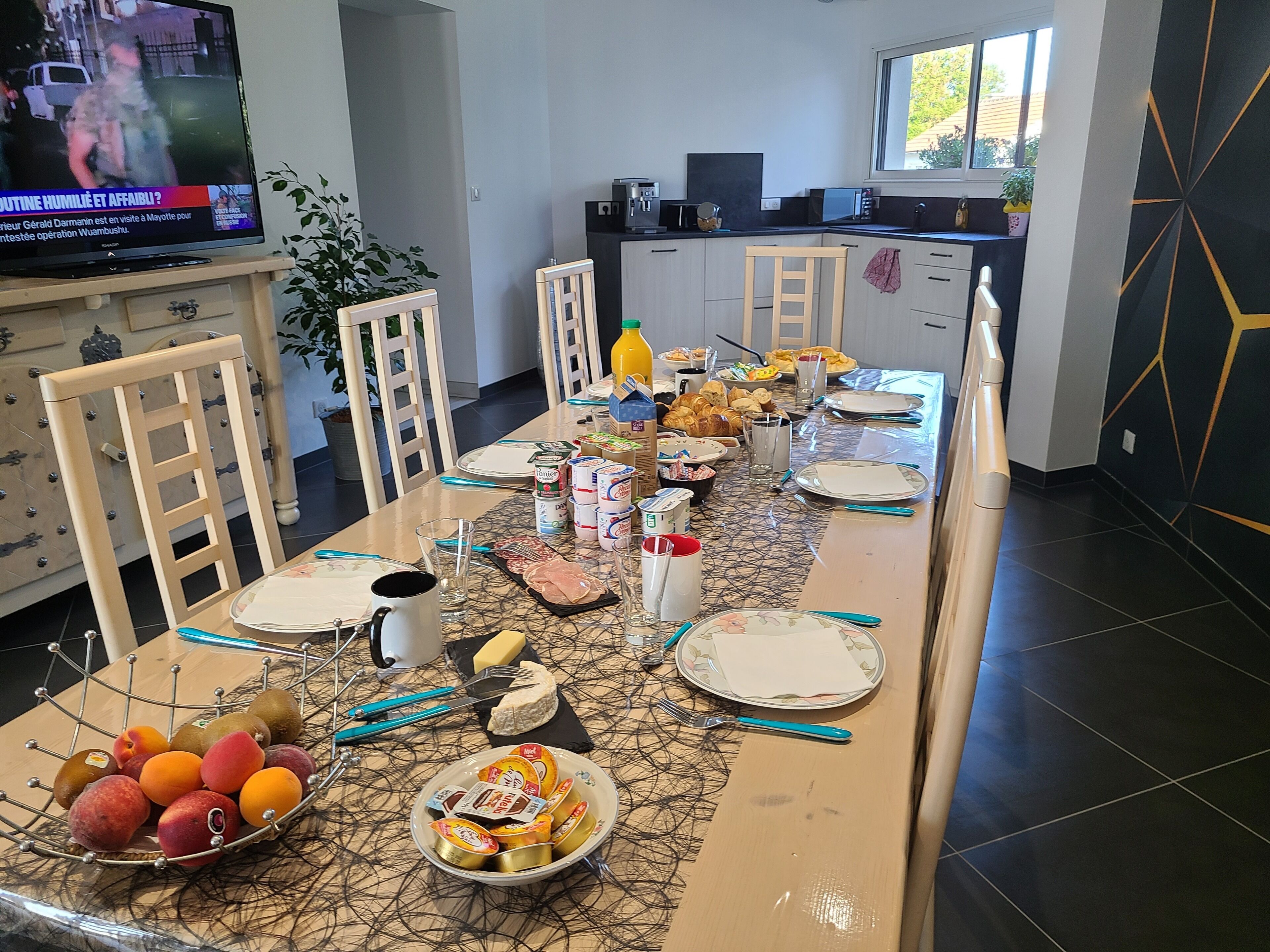 A dining area with a long table set for a meal, surrounded by chairs.