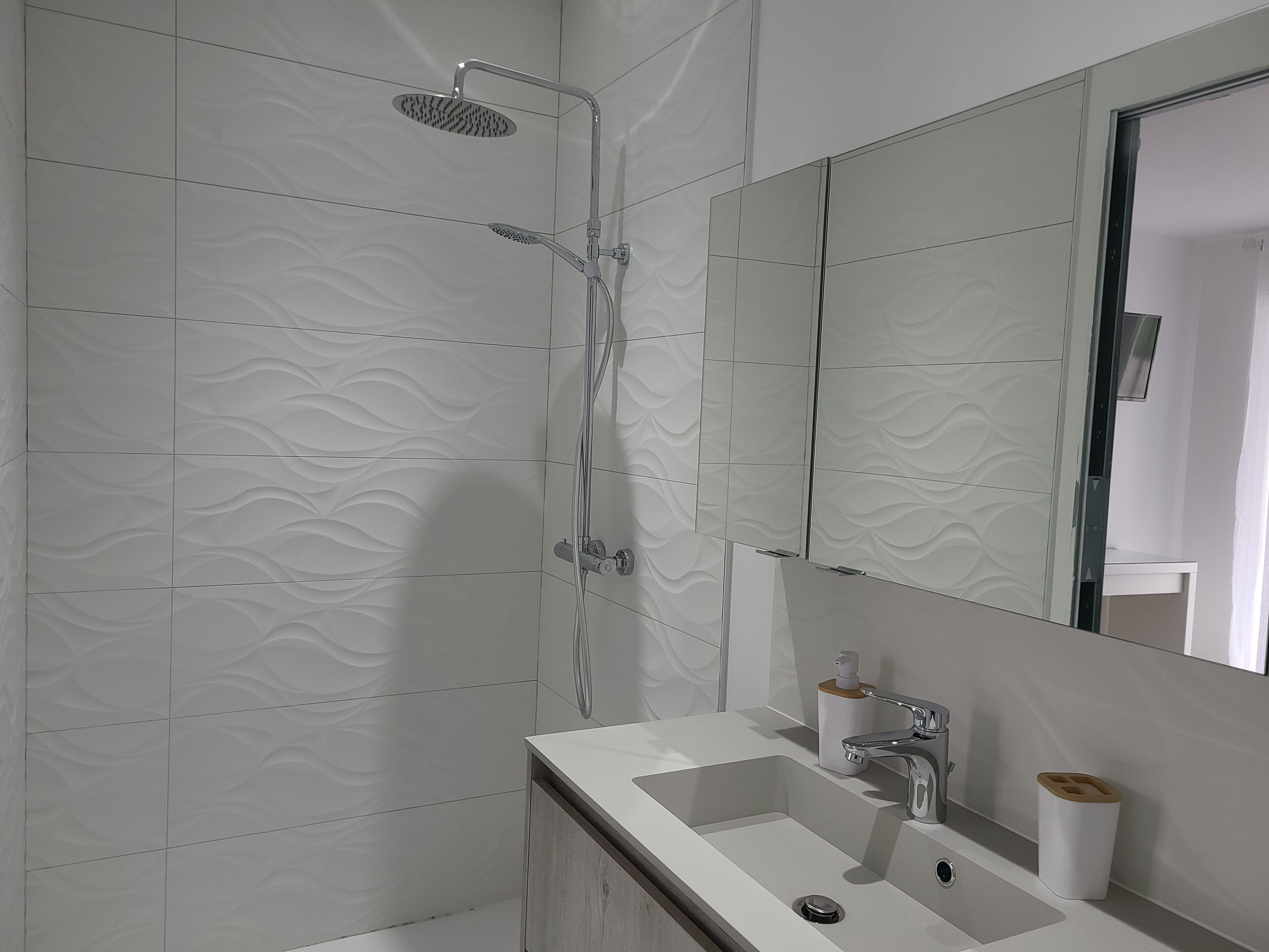 A modern bathroom with a shower, a sink, and a mirror.