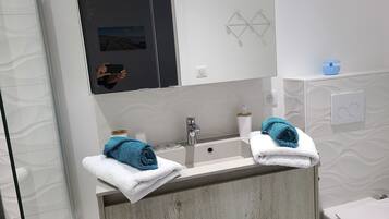 A modern bathroom with a large mirror, two sinks, and a towel rack.