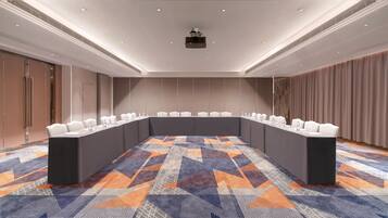 A conference room with a long table, white chairs, and a projector on the ceiling.