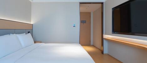 A modern hotel room with a large bed, a TV mounted on the wall, and a wooden floor.