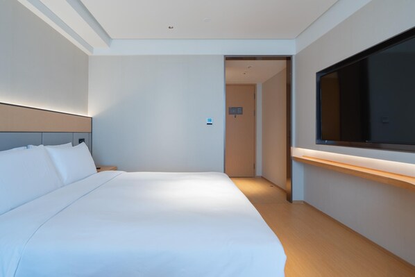 A modern hotel room with a large bed, a TV mounted on the wall, and a wooden floor. - Ji Hotel Guangzhou Tianhe Sports Center (Guangzhou)