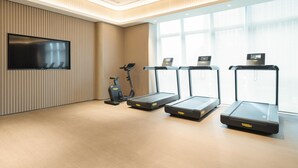 A modern gym with treadmills, an elliptical, and a TV on the wall. - Ji Hotel Guangzhou Tianhe Sports Center (Guangzhou)