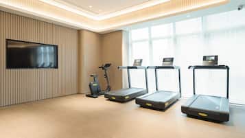 A modern gym with treadmills, an elliptical, and a TV on the wall.